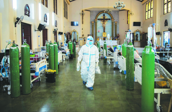 A health worker walks around to check on coronavirus disease patients admitted in the chapel of Quezon City General Hospital turned into a COVID-19 ward, in Quezon City, Philippines, August 20, 2021. (REUTERS)