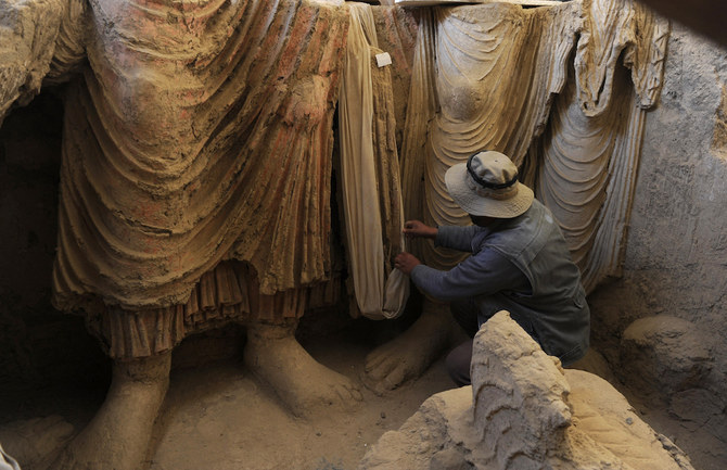 An Afghan archaeologist with ancient Buddha statues. Cultural workers have rushed to protect precious artefacts ahead of the Taliban’s arrival. (AFP/File Photo)