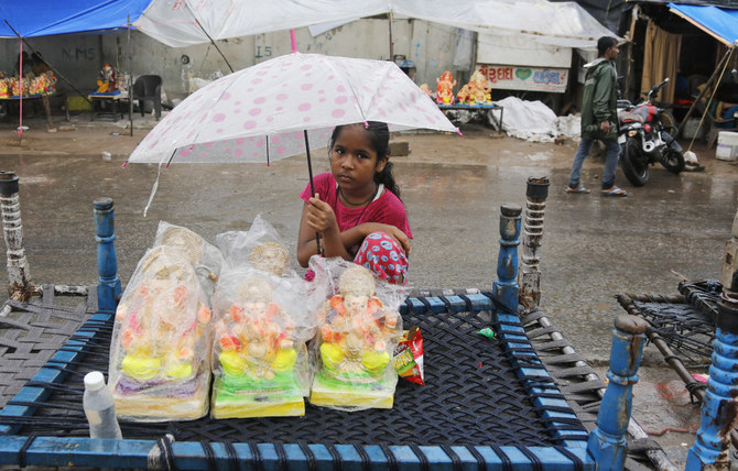 A girl selling idols of elephant-headed Hindu god Ganesha holds an umbrella to protect them from the rain during Ganesh Chaturthi festival celebrations in Ahmedabad, India, Friday, Sept. 10, 2021. (AP)
