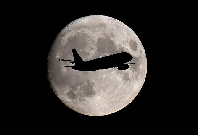 A passenger plane passes in front of the moon as it makes its final landing approach to Heathrow Airport in London. (Reuters/File Photo)