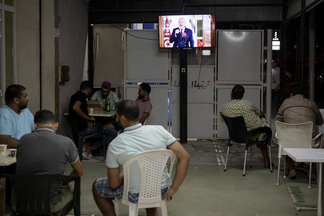 Tunisians sit in a cybercafe in Tunis, on September 20, 2021 as they watch television and listen to Tunisia's President Kais Saied delivering a speech. (File/AFP)
