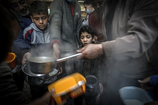 A boy waits as Palestinian Walid al-Hattab (R) distributes soup to people in need during the Muslim fasting month of Ramadan in Gaza City, amid the COVID-19 pandemic. (AFP/File Photo)