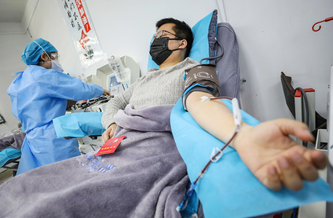 This photo taken on February 18, 2020 shows a doctor (R) who has recovered from the COVID-19 coronavirus infection donating plasma in Wuhan in China's central Hubei province. (AFP)