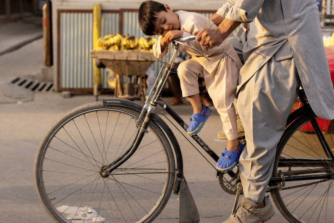 A boy sleeps as he rides a bicycle in Kabul, Afghanistan October 18, 2021. (REUTERS)