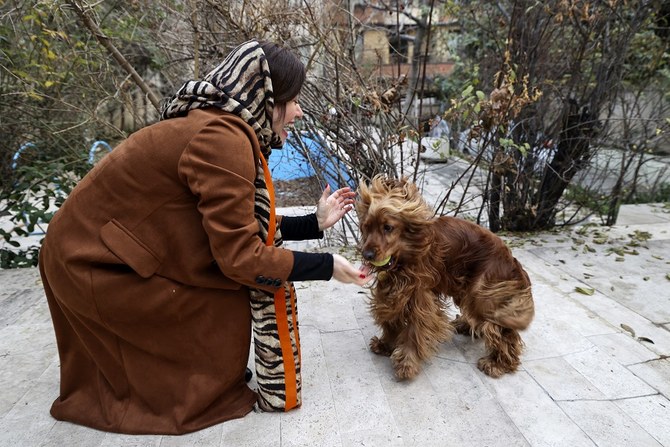 An Iranian woman plays with her dog in a yard near her house in northern Tehran, on December 5, 2021. (AFP)
