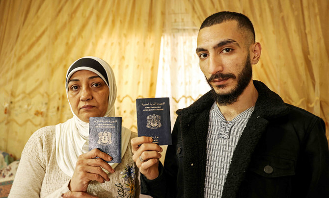 Syrian refugees Lina Moustafa Hassoun and her son Nawras Deeb pose with their expired Syrian passports in a house in Gaza City on December 5, 2021. (AFP)