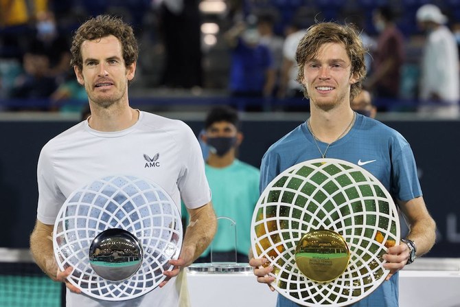 First-place winner Andrey Rublev of Russia holds up his trophy alongside second-place winner Andy Murray of Britain during the awards ceremony after the final match of the Mubadala World Tennis Championship. (AFP)