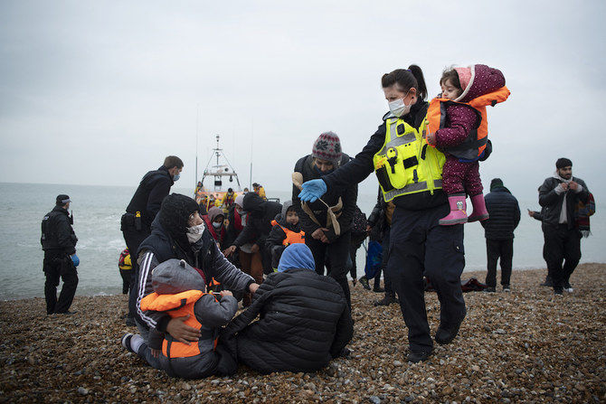 A member of the UK Border Force (R) helps child migrants on a beach in Dungeness, on the south-east coast of England, on Nov. 24, 2021 after being rescued while crossing the English Channel. (AFP)