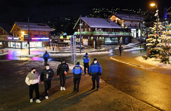 Police officers stand at the centre sqaure of the Swiss Alpine resort of Verbier to prevent people from gathering for the New Year on early January 1, 2021. (AFP)