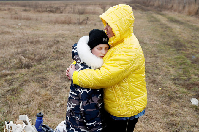 Nataliya Ableyeva, 58, comforts a child who was handed over to her at the Ukrainian side of the border by a father who was not allowed to cross at a border crossing in Beregsurany, Hungary, February 26, 2022. (REUTERS)