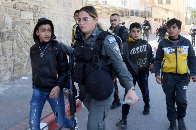 Israeli border police remove Palestinian children from the vicinity of the Ibrahimi Mosque in the divided West Bank city of Hebron on February 28, 2022. (AFP)