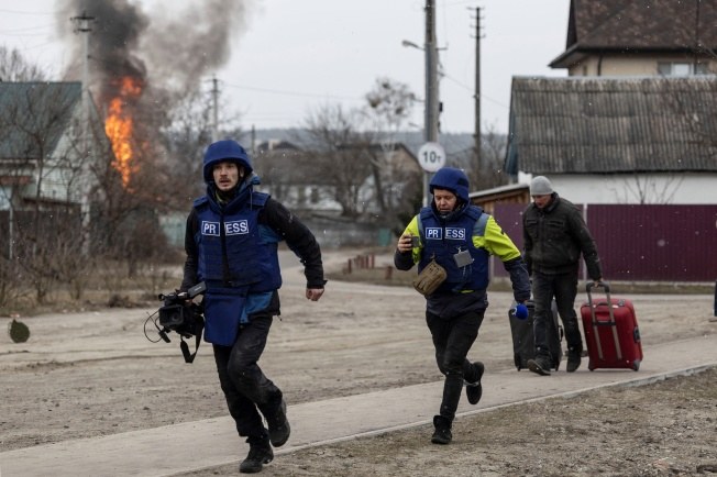Journalists running for cover in Irpin, Ukraine on March 6, 2022, after heavy Russian shelling. (Reuters)