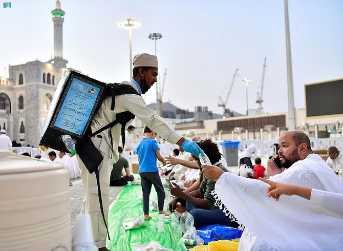 An employee at the Grand Mosque in Makkah hands out bottles of Zamzam water before iftar during Ramadan. (File/SPA)