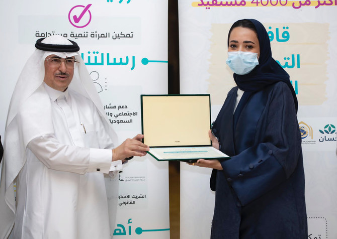Thikra Al-Abdul Latif, director of the Food Empowerment Convoy 2022 project, receives a certificate of thanks from Abdul Wahab Mohammed Al-Faiz after the launch of the project on Sunday in Riyadh. (Supplied)