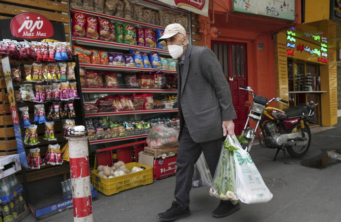An elderly man carries his shopping in front of a grocery store in Tehran, Iran, Wednesday, May 11, 2022. (AP)