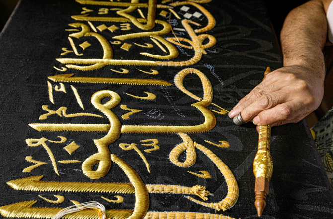 An embroiderer sews with gold thread a verse from the Holy Koran onto a replica of the Kiswa. (AFP)