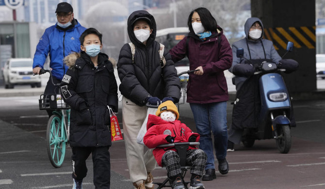A child wearing a mask is pushed across a road in Beijing, Friday, Dec. 2, 2022. (AP)