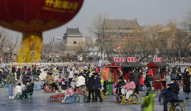 Visitors enjoy skating on the crowded frozen Houhai Lake near the Drum Tower, background, in Beijing, Monday, Jan. 30, 2023. (AP