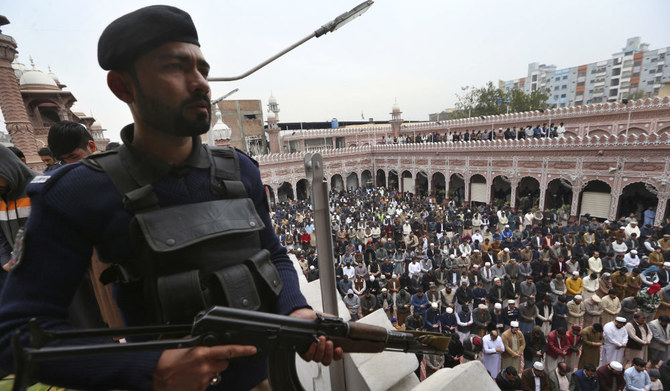 A police officer stands guard as people take part in Friday prayers at a mosque, in Peshawar, Pakistan, Friday, Feb. 3, 2023. 