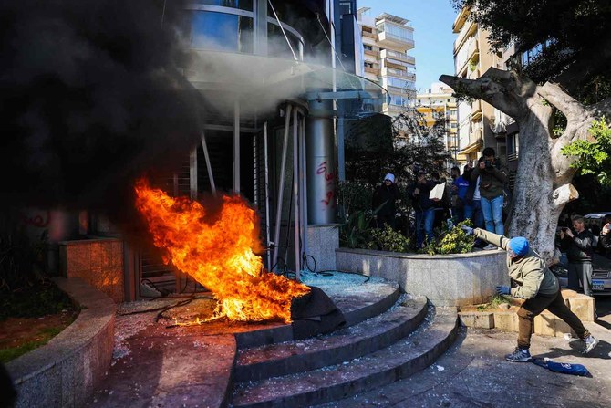A protester throws a brick at a bank after setting fire to tyres during a demonstration in Beirut on February 16, 2023. (AFP)