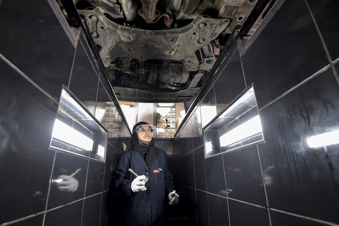 A Saudi mechanic walks in the inspection trench beneath a vehicle at a repair and service center. (Supplied)