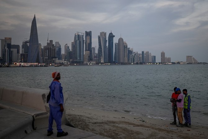 Migrant workers stand in front of the Doha skyline. (File/AFP)
