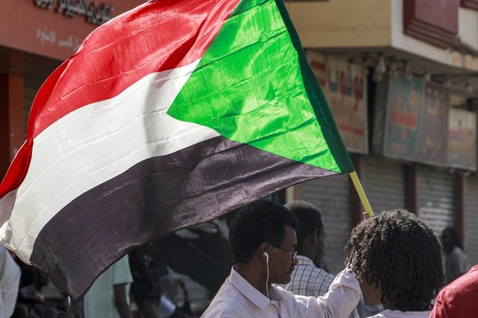 A man waves a Sudanese national flag while taking part in a protest march. (File/AFP)