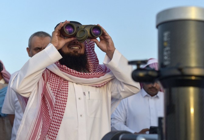 A Saudi man uses binoculars to spot the first crescent of the moon, marking the start of the holy month of Ramadan, in Taif.