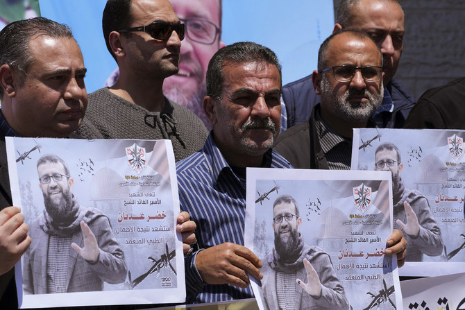 Palestinians hold pictures of Khader Adnan, a leader in the militant Islamic Jihad group, who died in Israeli prison.