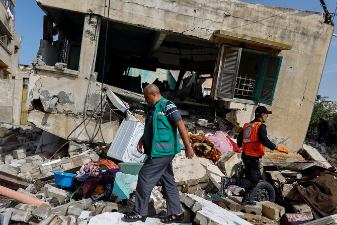 Palestinian rescue workers walk amid rubble after Islamic Jihad commander Ahmed Abu Daqqa was killed in an Israeli strike.