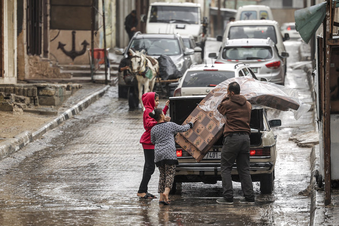 A man is assisted by children as he unloads mattresses from the back of a vehicle at Al-Shati camp for Palestinian refugees.