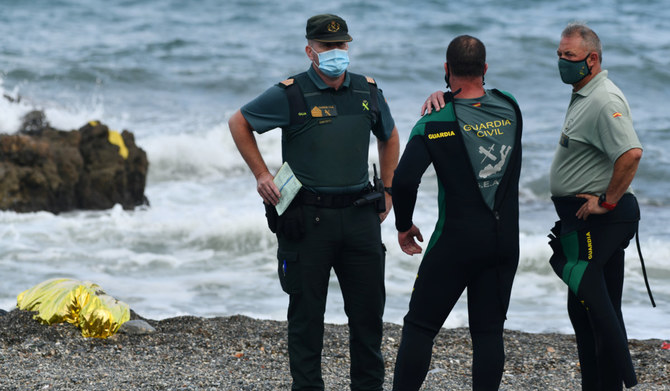 Spanish Guardia Civil members stand next to the body of a migrant at the beach of the Spanish enclave of Ceuta on May 20, 2021. 