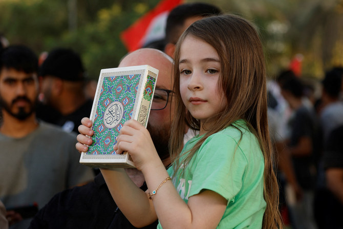 A child holds the Qur’an during a protest near the Green Zone against the burning of a copy of the Quran in the Swedish capital.