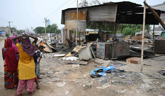 People stand next to a burnt strucutre in Gurugram, Haryana State, on August 4, 2023, following sectarian riots. (AFP)