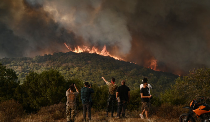 People look at the wildfire raging in a forest in Sikorahi, near Alexandroupoli, northern Greece, on August 23, 2023. (AFP)