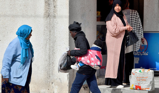A woman with her baby on her back walks in the Tunis suburb of Bhar Lazreg on February 24, 2023. (AFP)