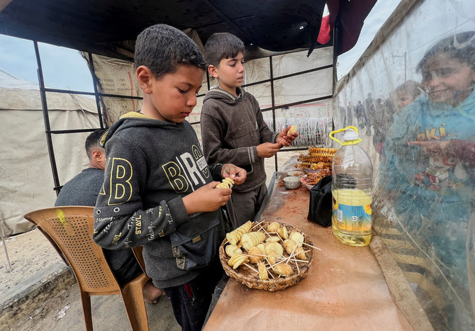 Displaced Palestinian boys sell homemade potato chips outside a tent camp in Rafah in the southern Gaza Strip, February 13,2024.