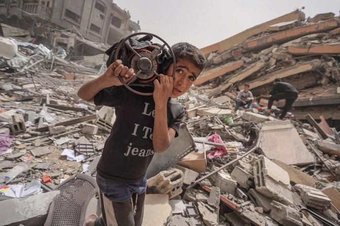 A Palestinian carries a gas cooker as he walks amidst the debris of a destroyed building in the city of Nuseirat.