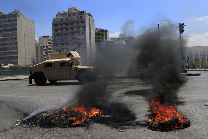 A Lebanese army vehicle passes next of burned tires that set on fire by protesters to block a main highway in Beirut on June 17, 2021, during a protest against the economic crisis in Lebanon. (AP Photo/Hussein Malla)