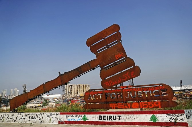 A gavel monument symbolizing justice is seen in front of the damaged grain silos at Beirut port on August 4, 2021, as Lebanon marks a year since a cataclysmic explosion ravaged the capital. (AFP)