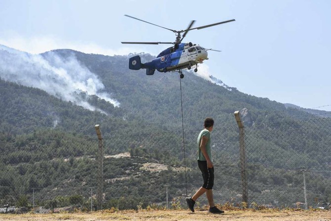 A firefighting helicopter takes water from a lake in Akcaova Village, near Cine, Aydin, Turkey on Aug. 7, 2021. (AP Photo)