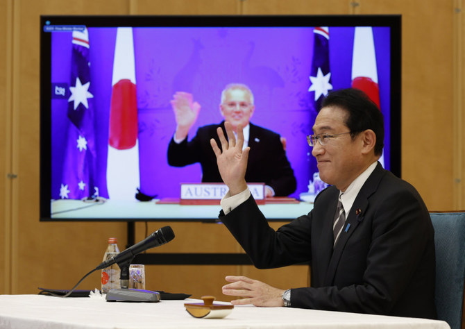 Japan's PM Fumio Kishida, right, and Australia's PM Scott Morrison seen on screen, attend a virtual summit to sign the Reciprocal Access Agreement on Jan. 6, 2022. (Issei Kato/Pool Photo via AP)