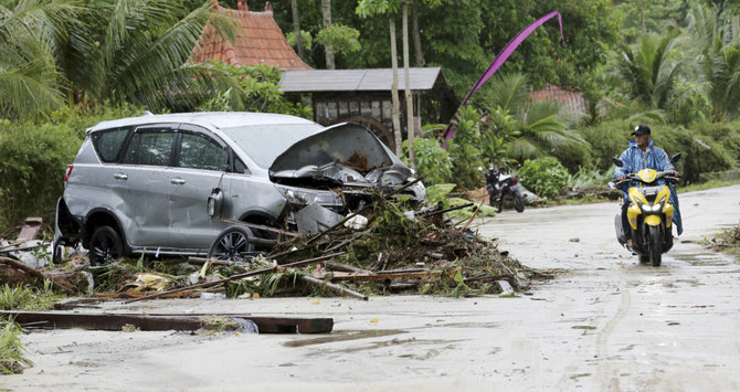 A motorist passes a car damaged by a tsunami, in Tanjung Lesung, Indonesia, Monday, Dec. 24, 2018. (AP)