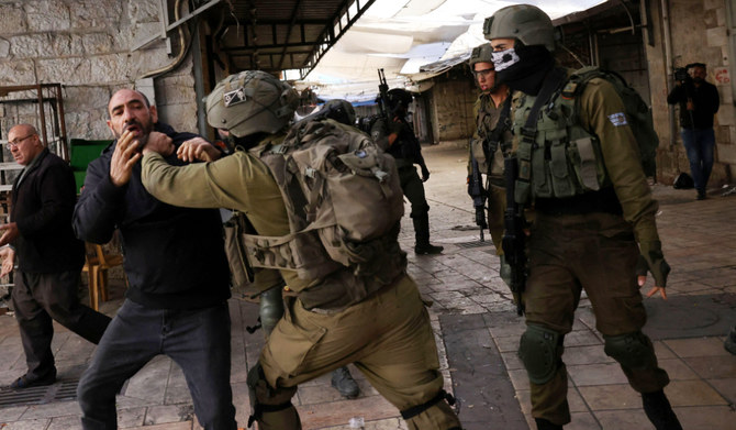  Israeli security forces hold back a Palestinian man in the occupied West Bank city of Hebron, on November 19, 2022 (AFP)