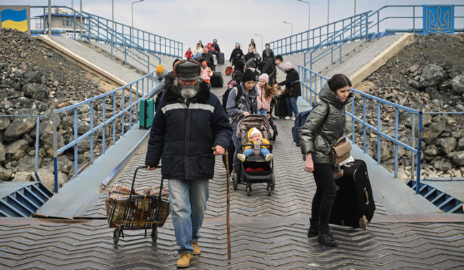 Ukrainian refugees embark on a ferry to cross the Danube river at the Ukrainian-Romanian border on March 25, 2022. (AFP)