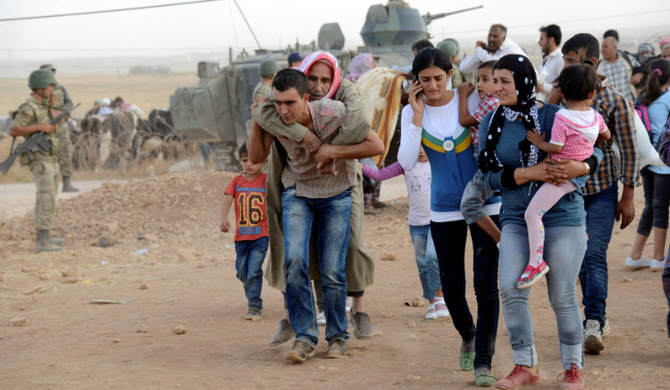 Syrian Kurds walk after crossing into Turkey at the Turkish-Syrian border. (REUTERS)